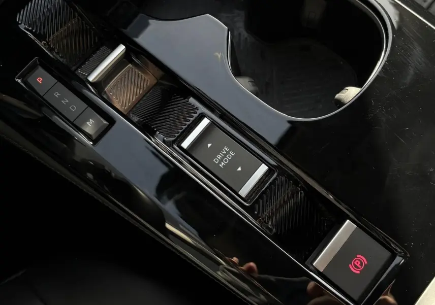 Gros plan sur la console centrale noire brillante du Citroën C5 X avec commandes boîte auto et mode de conduite.