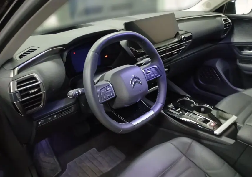 Vue intérieure côté gauche montrant les sièges avant en cuir noir et la console centrale du Citroën C5 X 2024.