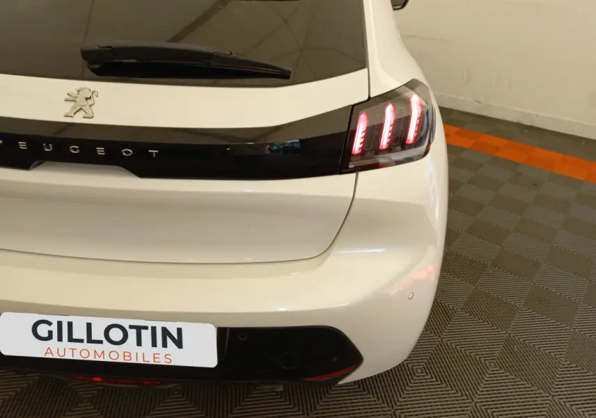Vue arrière droite d'une Peugeot 208 blanche avec feux arrière LED et logo Peugeot visible sur le hayon.