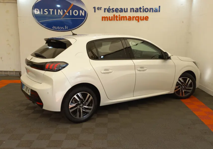 Peugeot 208 blanc vue de profil droit en intérieur, avec feux arrière LED et jantes alliage distinctives.