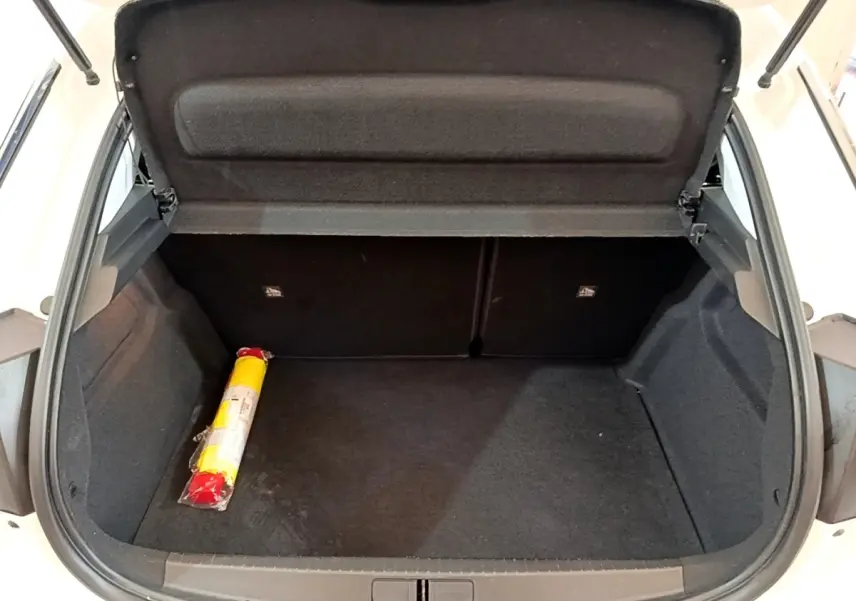 Coffre ouvert d’une Opel Corsa blanche, vue de l’arrière montrant un espace de chargement vide avec un triangle de signalisation.