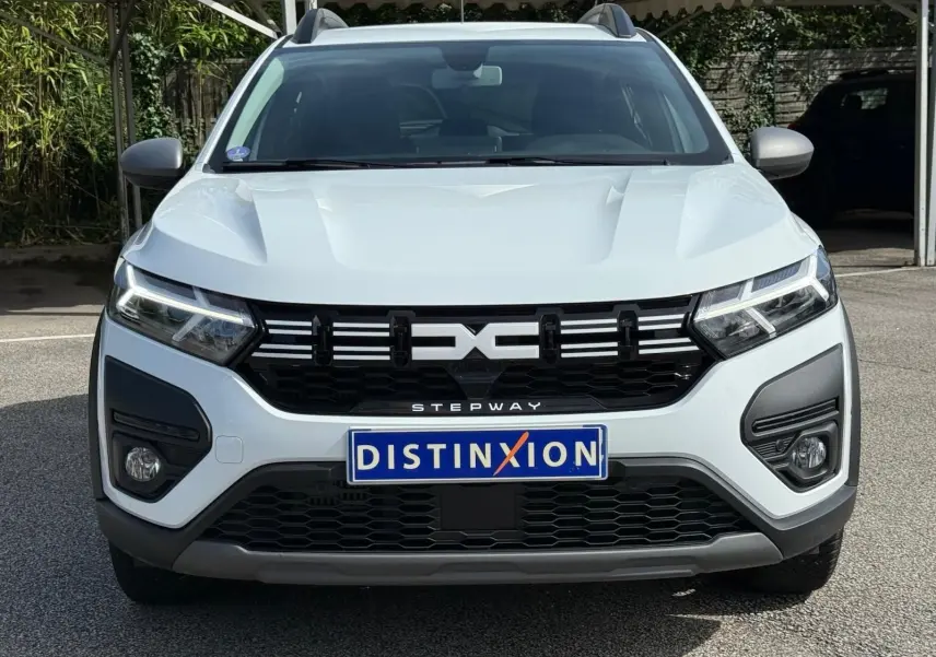 Vue frontale d'une Dacia Sandero Stepway blanche 2023 avec calandre noire et feux LED distinctifs.