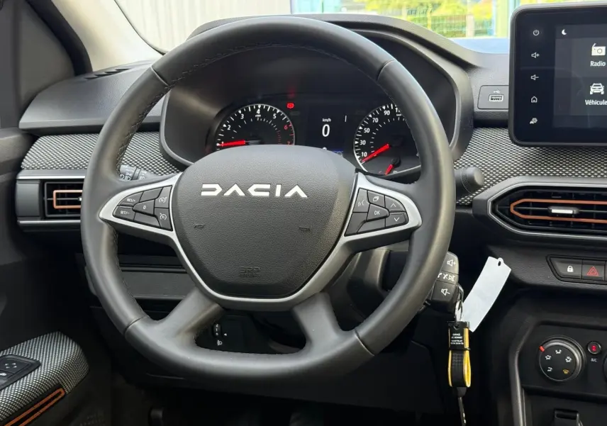 Vue rapprochée du volant noir de la Dacia Sandero 2023 avec tableau de bord et écran tactile visibles.