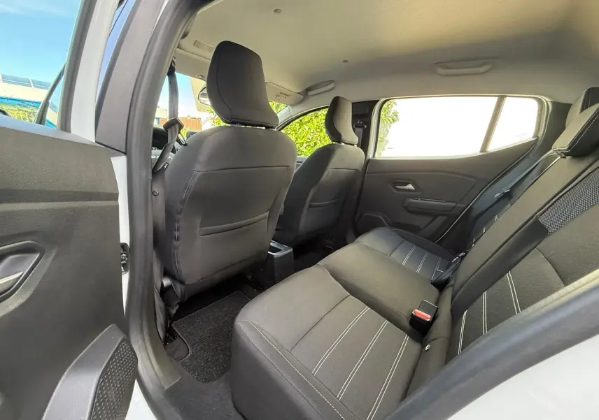 Vue intérieure arrière côté gauche montrant les sièges noirs avec surpiqûres blanches d'une Dacia Sandero blanche 2023.