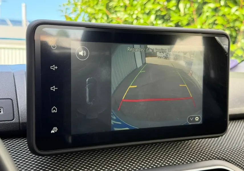 Écran tactile intérieur montrant la caméra de recul du Dacia Sandero blanc version Stepway 2023 avec aides au stationnement.