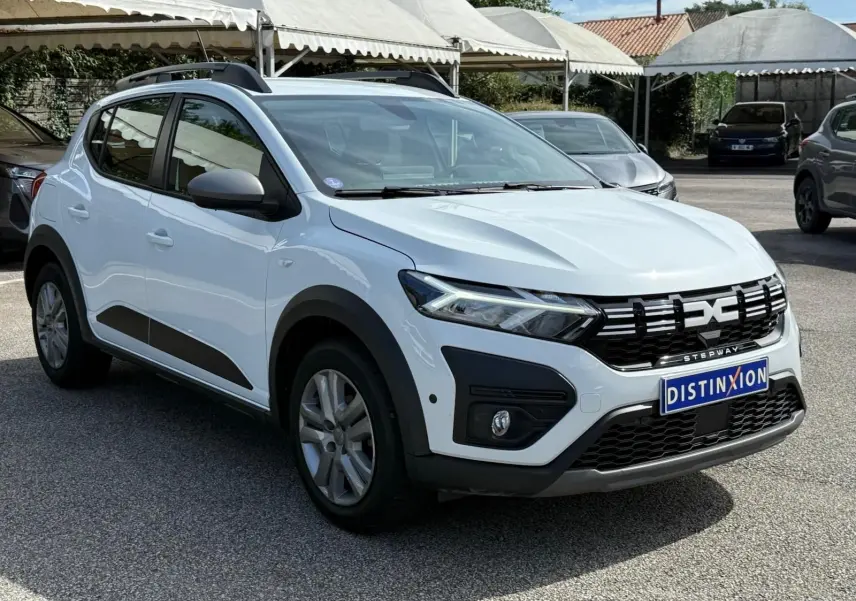Vue 3/4 avant droite d'une Dacia Sandero Stepway blanche 2023 avec calandre noire et protections latérales noires.