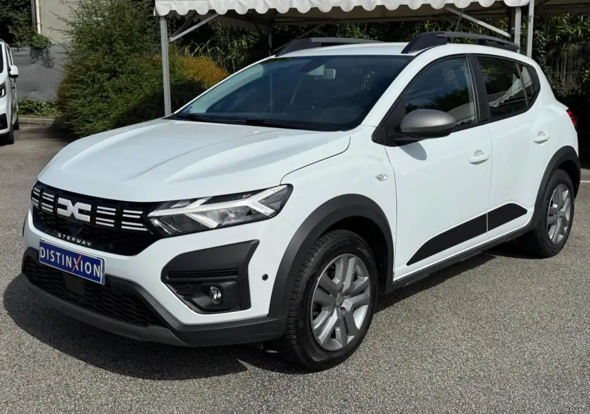 Vue 3/4 avant droite d'une Dacia Sandero Stepway blanche 2023 avec protections noires et jantes alliage.