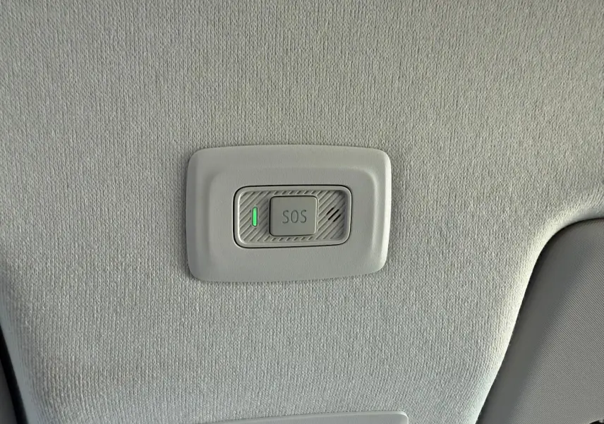 Bouton SOS éclairé en vert sur le plafond intérieur gris clair d'une Dacia Sandero blanche 2023.