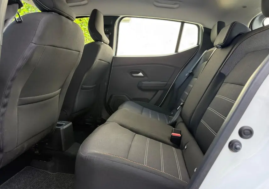 Vue latérale droite de l'habitacle arrière d'une Dacia Sandero blanche 2023, sièges noirs avec surpiqûres claires.