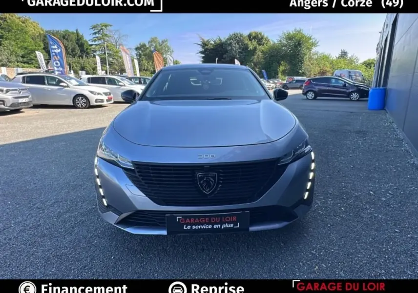 Vue avant frontale d'une Peugeot 308 gris clair avec calandre noire et feux LED verticaux allumés.