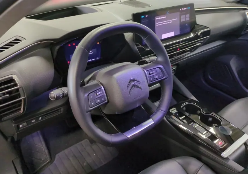 Intérieur du Citroën C5 X 2024 vu côté conducteur, volant cuir noir avec commandes intégrées et écran tactile 12 pouces.