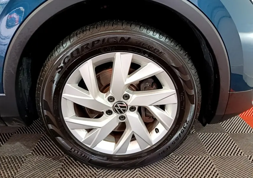 Gros plan sur la roue avant droite du Volkswagen Tiguan bleu, mettant en valeur la jante alliage et le pneu Pirelli Scorpion.