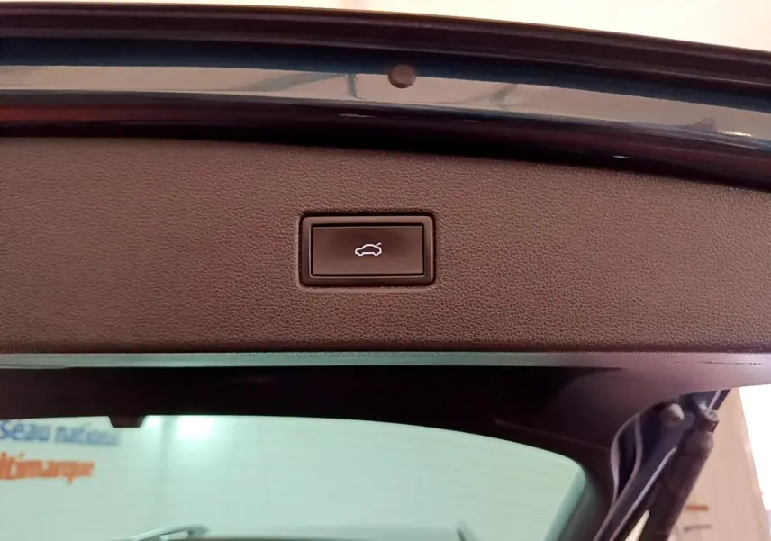 Bouton d'ouverture électrique du coffre sur la partie intérieure du hayon d'un Volkswagen Tiguan bleu.