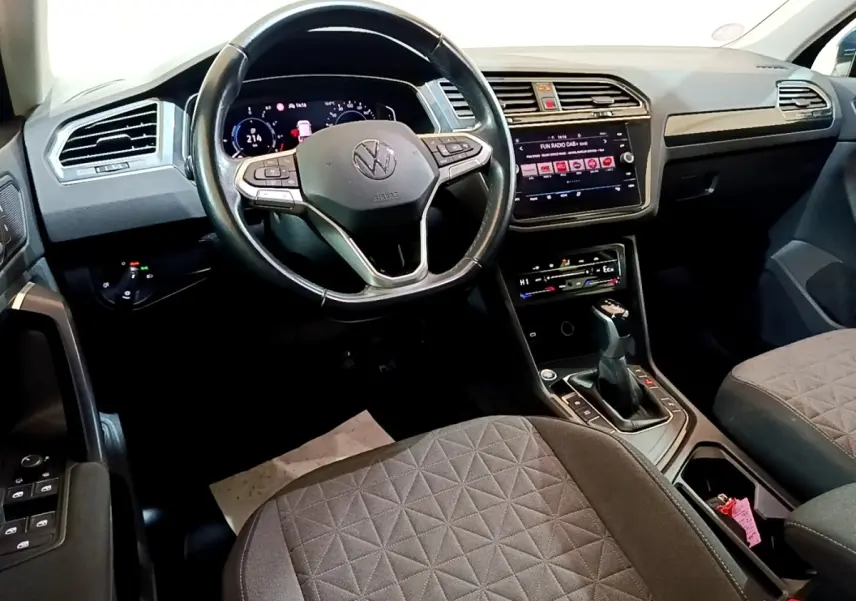 Vue intérieure avant du Volkswagen Tiguan 1.4 eHybrid 2021, volant cuir multifonctions et écran tactile central allumé.
