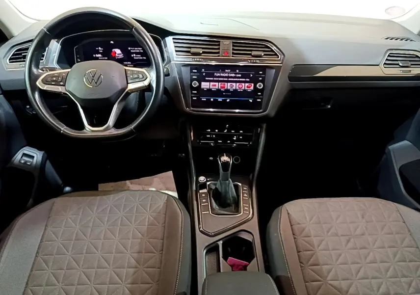 Vue intérieure du tableau de bord et console centrale du Volkswagen Tiguan 1.4 eHybrid, avec volant cuir et écran tactile.