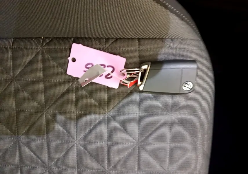 Clé Volkswagen posée sur un siège en tissu gris à motifs géométriques, intérieur du véhicule visible.