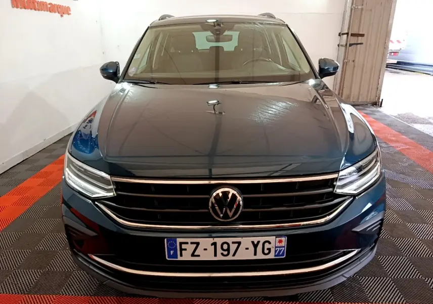 Vue avant d'un Volkswagen Tiguan bleu 1.4 eHybrid 245 DSG6 Life Business dans un garage lumineux.