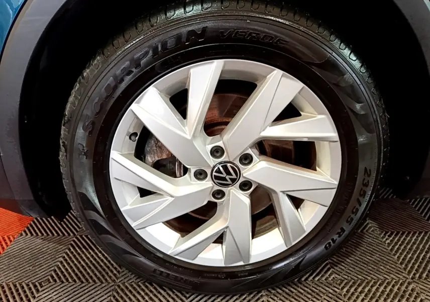 Gros plan sur la roue avant gauche du Volkswagen Tiguan bleu, mettant en valeur la jante argentée et le pneu Pirelli Scorpion Verde.