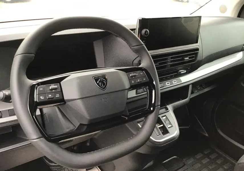 Vue intérieure centrée sur le volant et le tableau de bord du Peugeot Expert gris titane avec écran tactile et commandes intégrées.