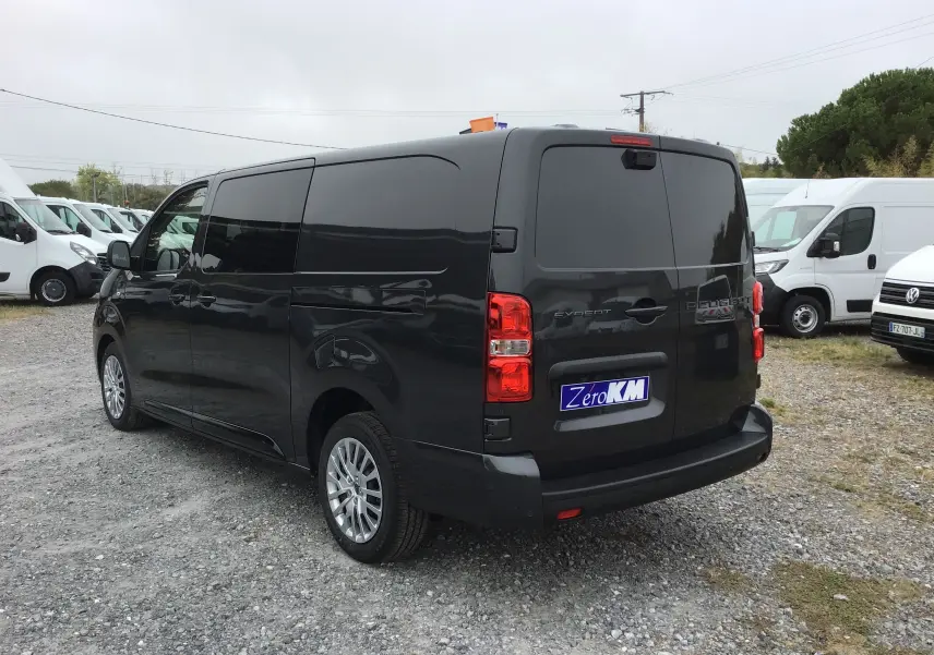 Vue 3/4 arrière droite d’un Peugeot Expert cabine approfondie gris titane avec vitres arrière teintées et jantes alliage.