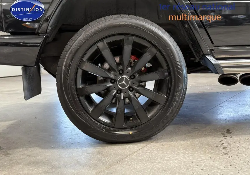 Gros plan sur la roue arrière droite noire avec jante AMG et sortie d’échappement chromée d’un Mercedes Classe G 2014.