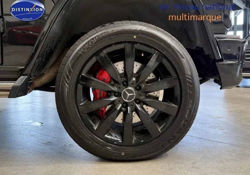 Gros plan sur la roue arrière gauche noire du Mercedes Classe G 5.5 63 AMG avec étrier de frein rouge visible.
