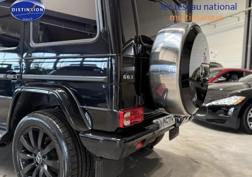 Vue 3/4 arrière droite d'un Mercedes Classe G 63 AMG noir avec roue de secours chromée et jantes noires.