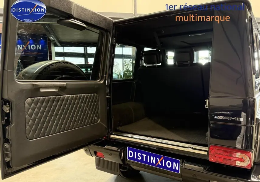 Vue arrière gauche d'un Mercedes Classe G 5.5 63 AMG noir avec porte arrière ouverte dévoilant le coffre spacieux.