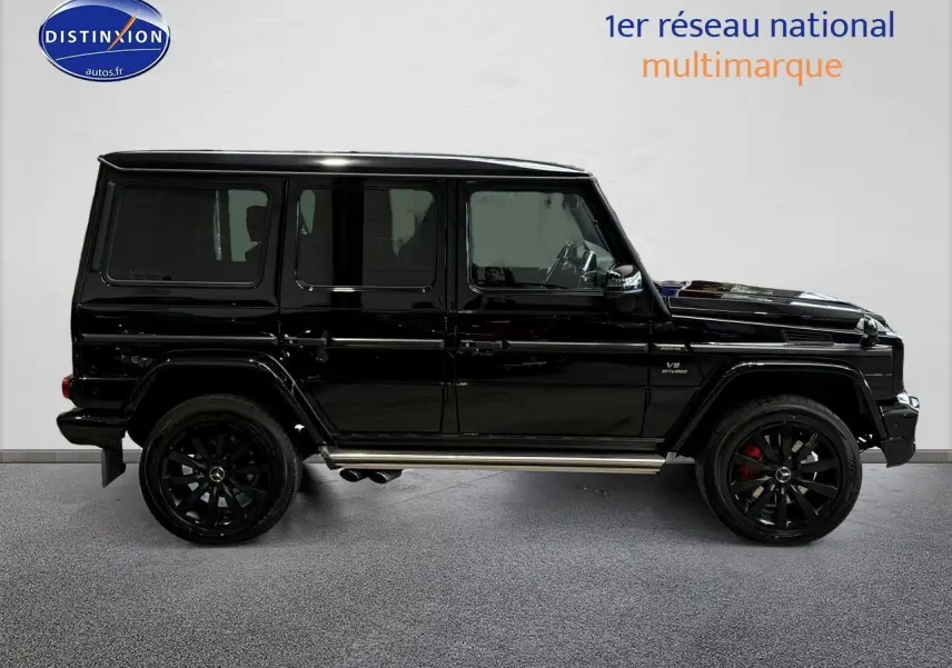 Profil côté gauche d'un Mercedes Classe G 5.5 63 AMG noir avec jantes noires et sorties d'échappement latérales chromées.