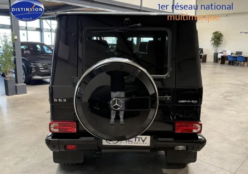 Vue arrière d'un Mercedes Classe G 63 AMG noir avec roue de secours intégrée et logo AMG visible.