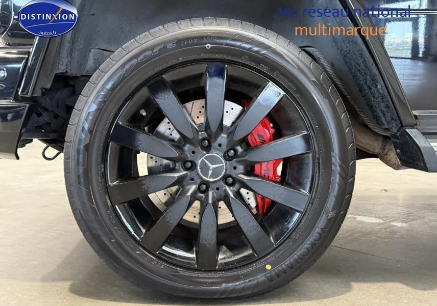 Gros plan sur la jante noire et l'étrier de frein rouge du côté gauche d'un Mercedes Classe G 5.5 63 AMG noir.