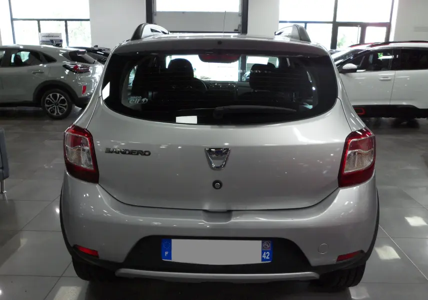 Vue arrière d'une Dacia Sandero Stepway gris platine 2016 en intérieur, avec logo et feux arrière visibles.