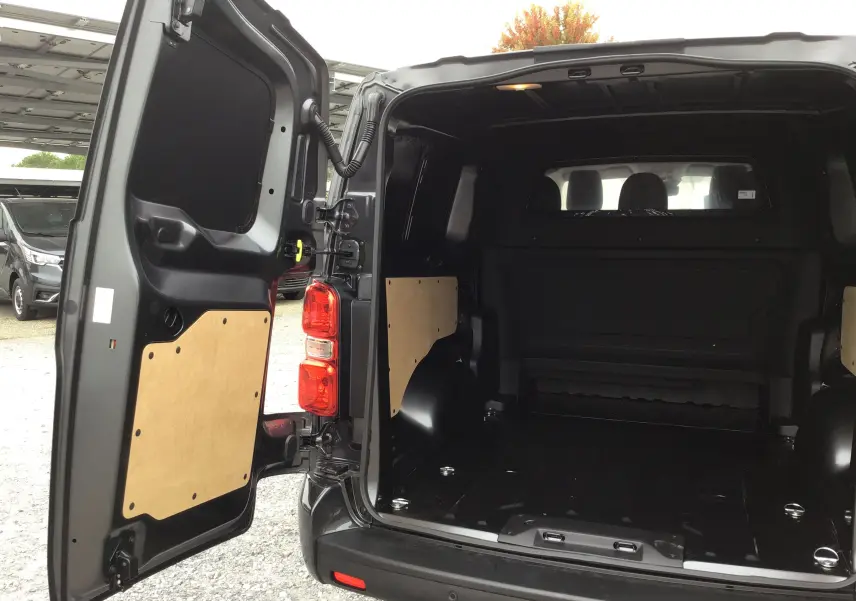Vue arrière ouverte du Peugeot Expert XL gris titane, montrant l’espace de chargement vide avec panneaux de protection en bois.