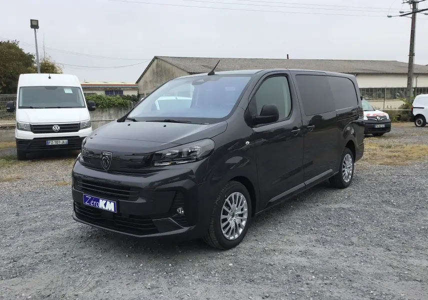 Peugeot Expert Cabine Approfondie gris titane vu en 3/4 avant droit sur un sol gravillonné, avec jantes alliage et calandre noire.