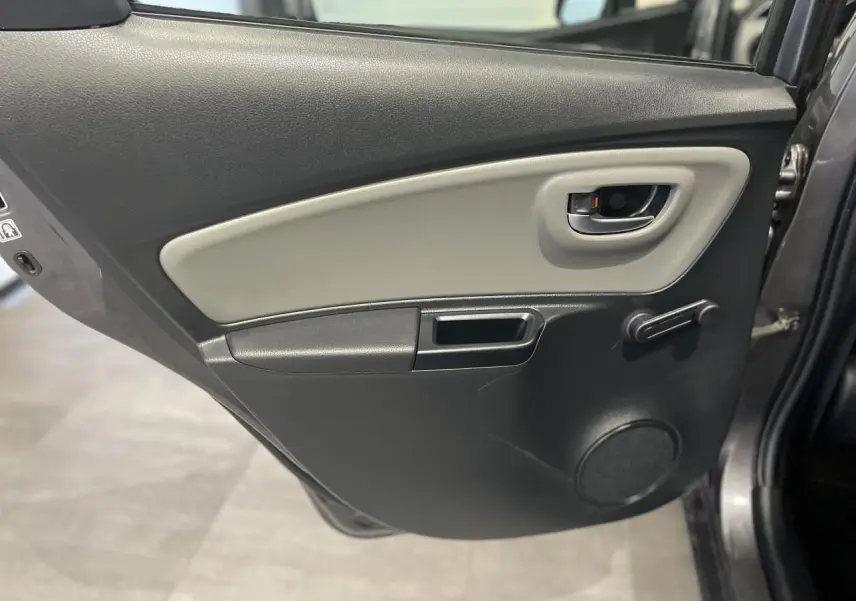 Vue rapprochée de la porte arrière droite gris foncé métallisé de la Toyota Yaris Hybride 2020 avec manivelle de vitre et poignée intérieure grise.
