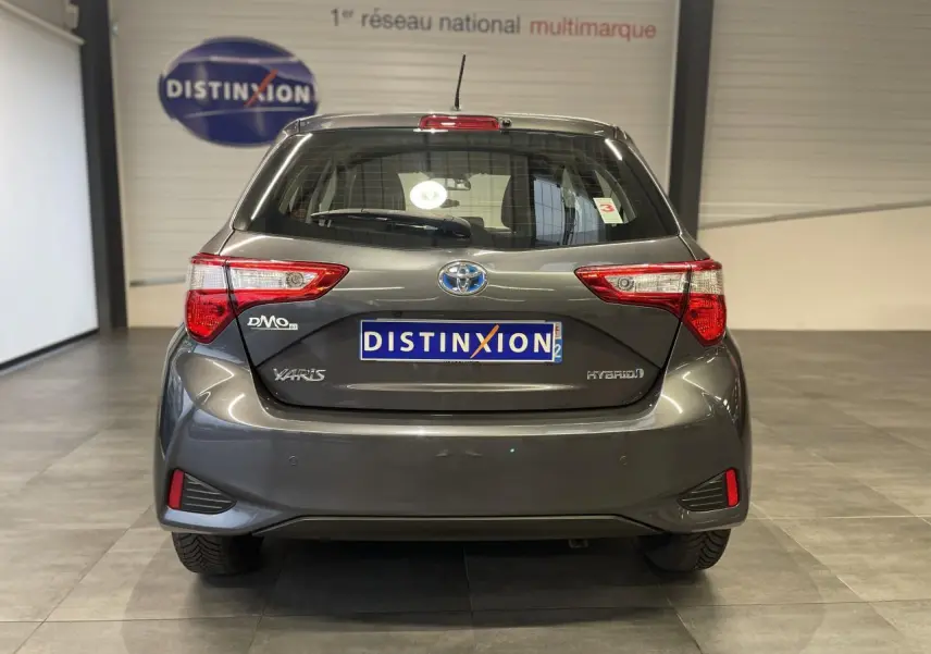 Vue arrière d'une Toyota Yaris hybride gris foncé métallisé avec feux arrière nets et logo distinctif.