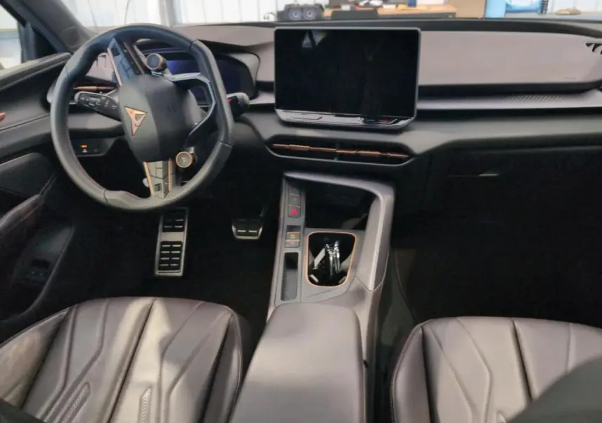 Intérieur du CUPRA TERRAMAR 1.5 e-Hybrid vu de face, avec tableau de bord noir texturé et volant sport cuir cuivré.