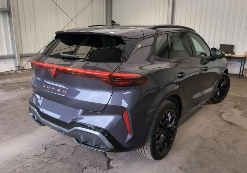 Vue 3/4 arrière droite du CUPRA TERRAMAR 2024 Dark Void avec jantes cuivrées et hayon électrique en intérieur d'atelier.