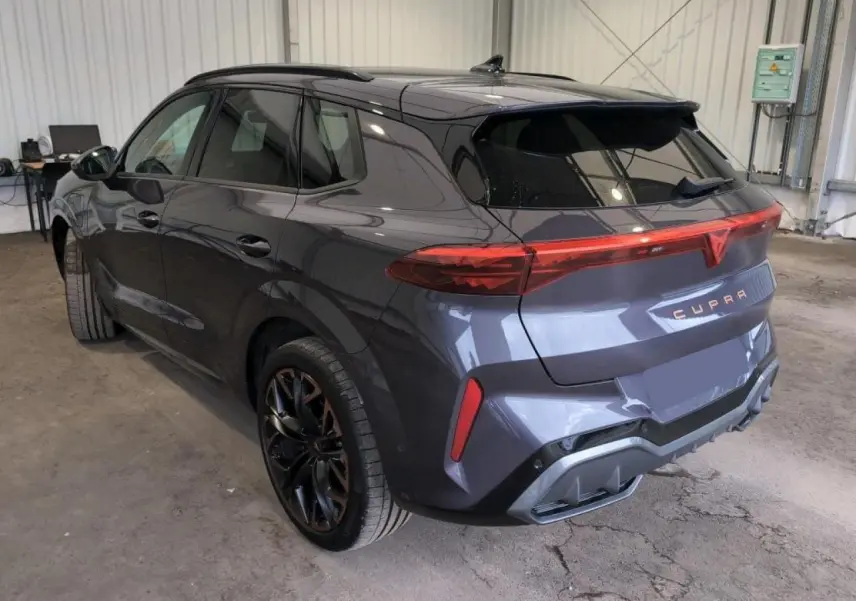 Vue 3/4 arrière droite du CUPRA TERRAMAR 2024 Dark Void avec jantes cuivrées et hayon électrique en intérieur d'atelier.