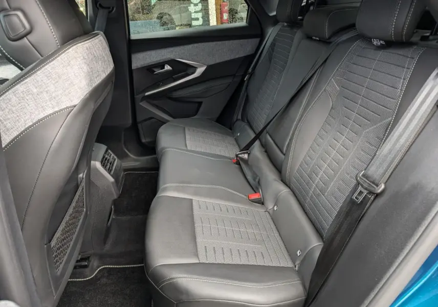 Vue intérieure côté gauche des sièges arrière en tissu gris et cuir noir du Peugeot 3008 GT hybride bleu métallisé 2025.
