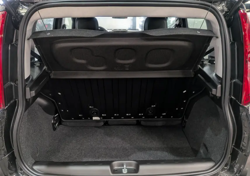 Coffre ouvert vu de l’arrière d’une FIAT Panda 1.0 70 CH Hybrid City noir cinéma, montrant l’espace de rangement et la tablette arrière.