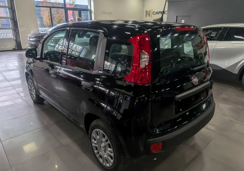 Vue 3/4 arrière droite d'une Fiat Panda 1.0 Hybrid City noire, en showroom avec feux arrière verticaux rouges bien visibles.