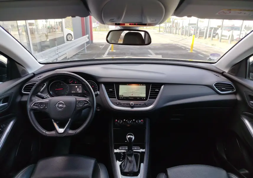 Vue intérieure frontale du tableau de bord noir de l'Opel Grandland X 1.6 Turbo avec écran central et volant multifonction.