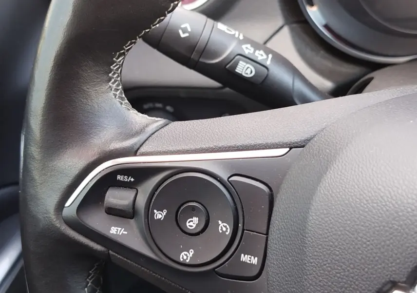 Gros plan sur les commandes de régulateur de vitesse au volant cuir noir de l’Opel Grandland X 2021.