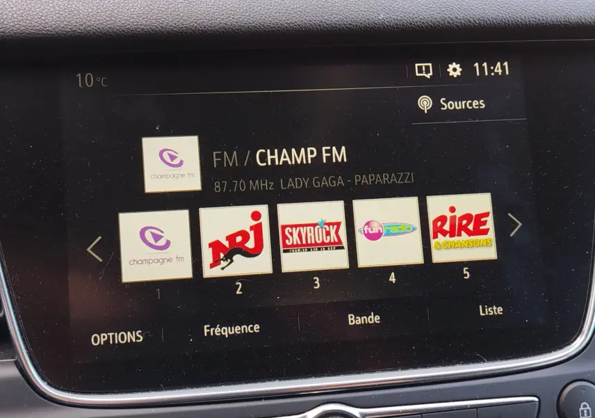 Écran multimédia intérieur de l’Opel Grandland X 2021 affichant les stations radio FM avec interface noire et bordure chromée.