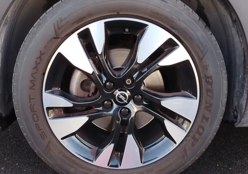 Gros plan sur la jante bi-ton noire et argentée avec logo Opel, montée sur un pneu Dunlop Sport Maxx.