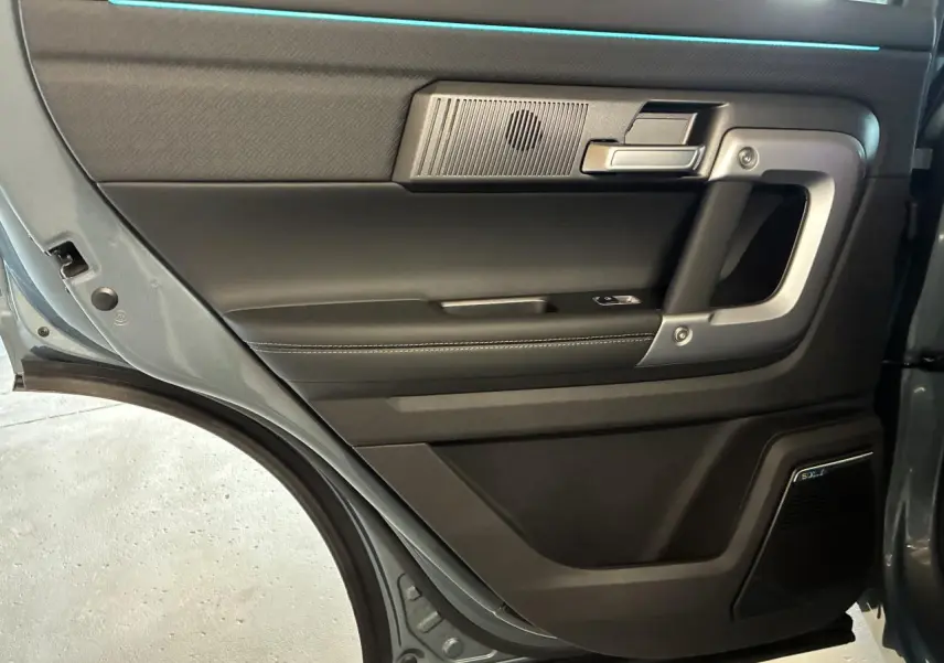 Vue intérieure de la porte arrière gauche du JAECOO J7 gris olive, avec haut-parleur Sony intégré et poignée argentée.