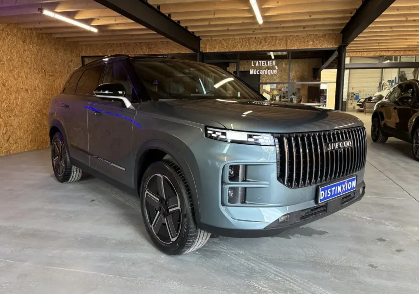SUV JAECOO J7 gris olive en 3/4 avant droit, avec calandre verticale noire et jantes alliage 19 pouces.