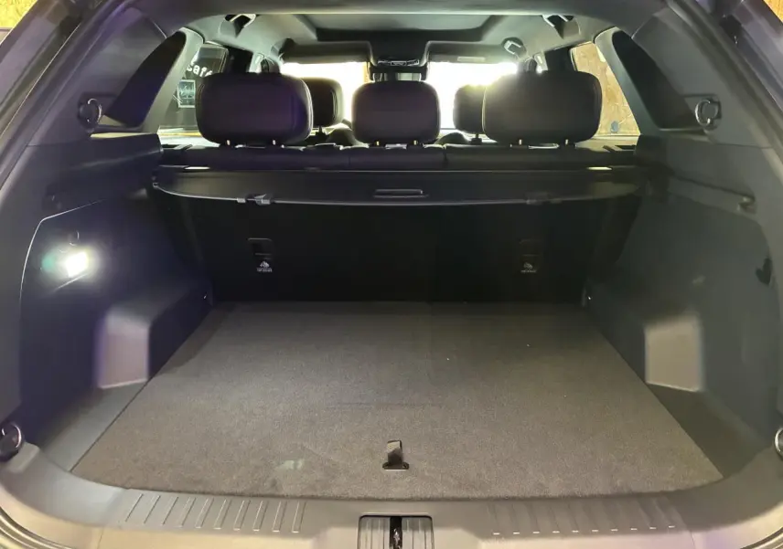Coffre ouvert vu de l'arrière du JAECOO J7 gris olive, intérieur noir et banquette arrière visible.