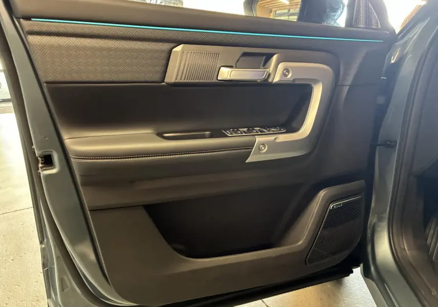 Vue intérieure côté conducteur de la porte du JAECOO J7 gris olive, avec habillage noir et haut-parleur Sony intégré.